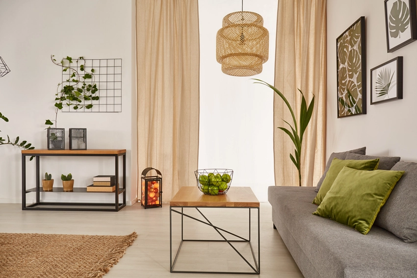A living room decorated with earth tones from the furniture to the shelving, flooring, décor, and drapery as recommended by Home Décor Craze. 