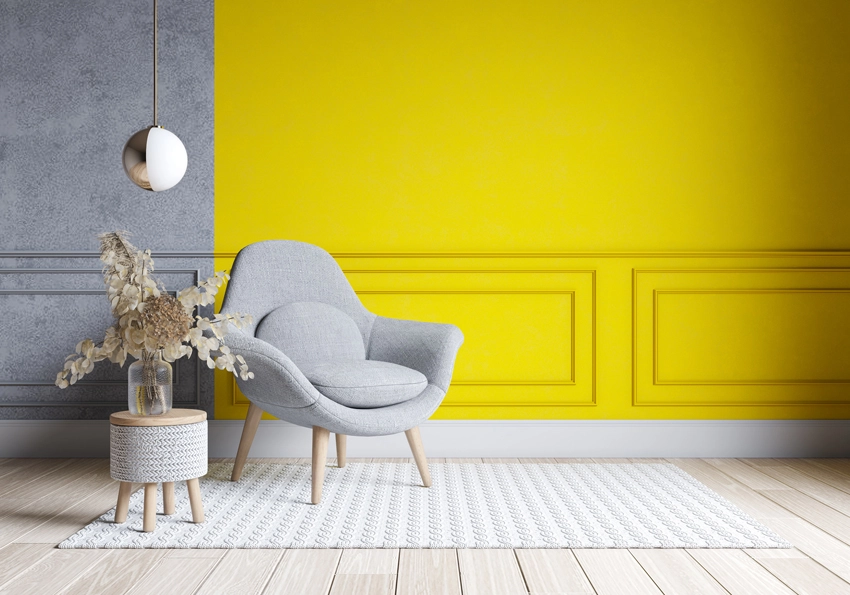 gray chair against a yellow and gray accent wall, as recommended by Home Décor Craze in their top 5 2021 home décor trends
