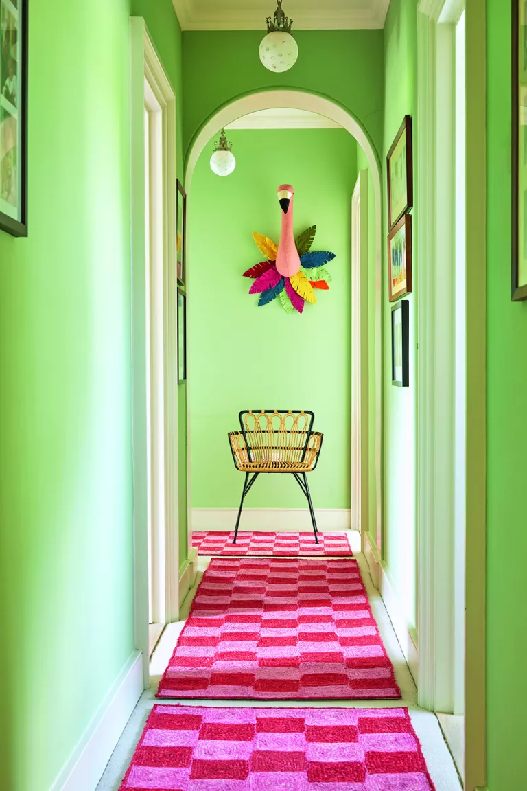 A hallway featuring neon pink checked rugs, a home décor design new to 2022, as found on HomeDecorCraze.