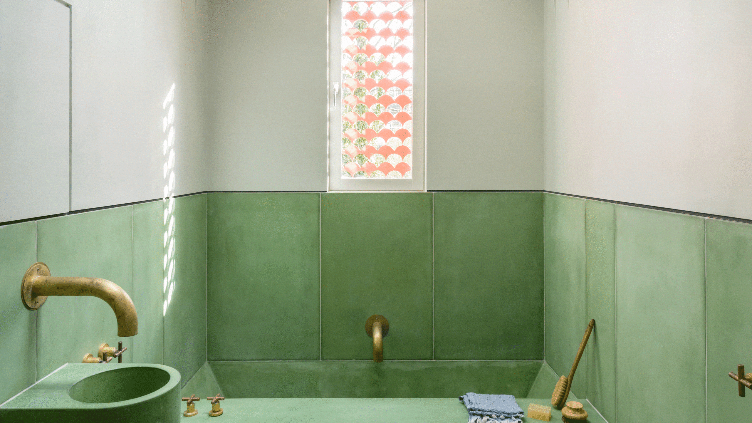 A bathroom with green colored concrete making up the floor, sink, and bathtub, with brass fixtures, as found on HomeDecorCraze.