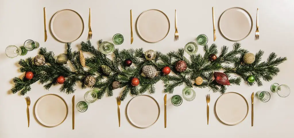 Flat-lay of Christmas table setting with white dinnerware and branches