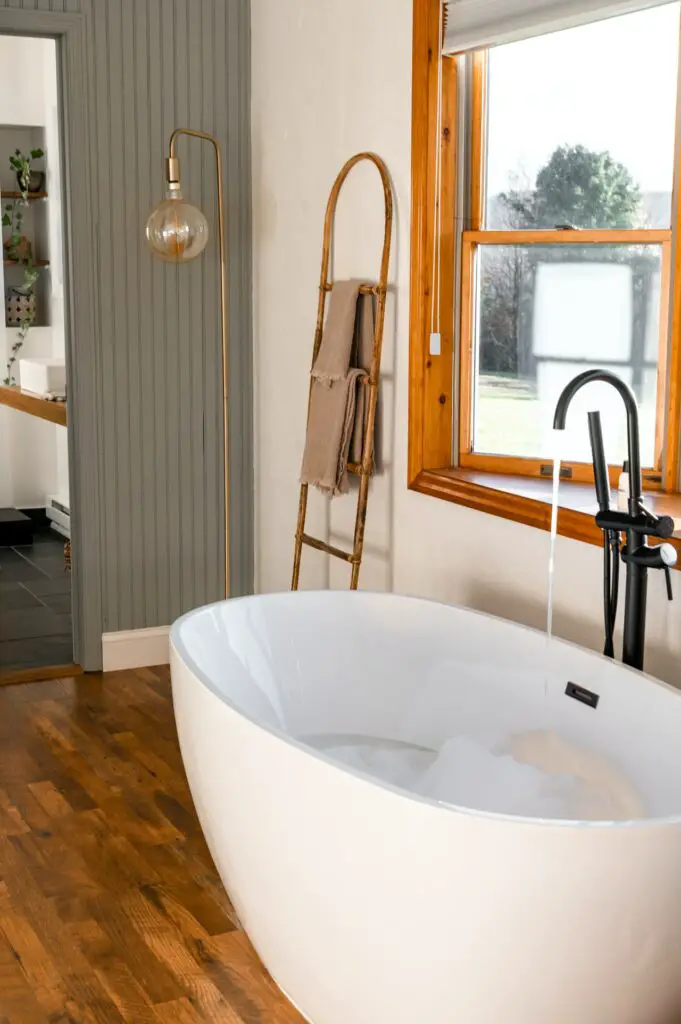 White free-standing soaker tub with black faucet.