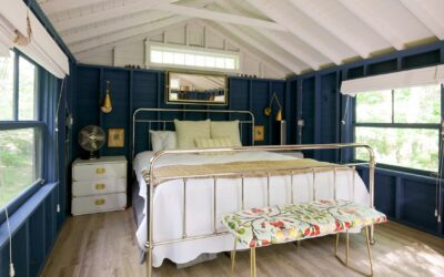 Brass bed with white coverlet and beige blanket in blue room.