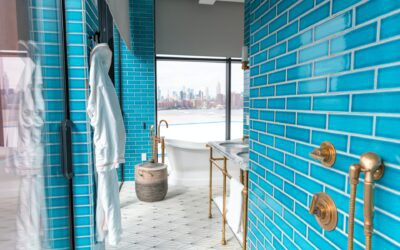 Bathroom with blue tiled walls and full-length window with city view.