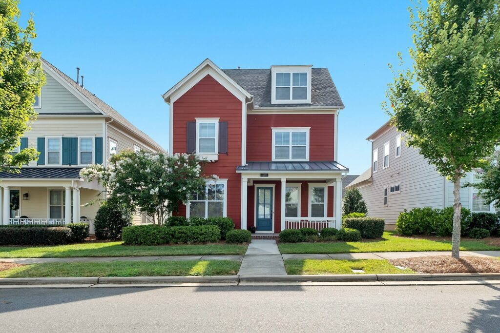 Red two story farmhouse with white trim and blue front door.